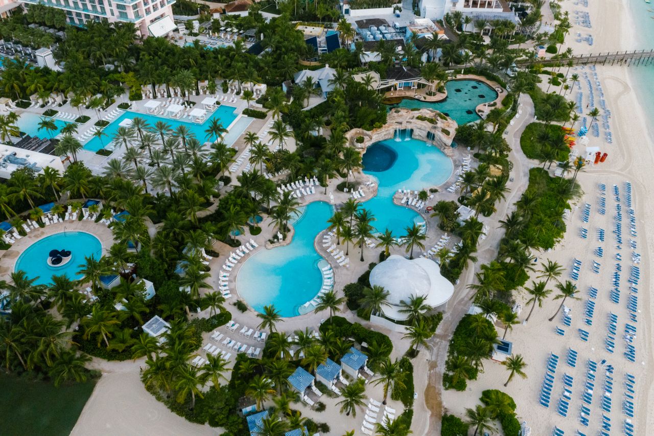 services-04 A stunning aerial view of a luxurious beachfront resort with swimming pools and palm trees.
